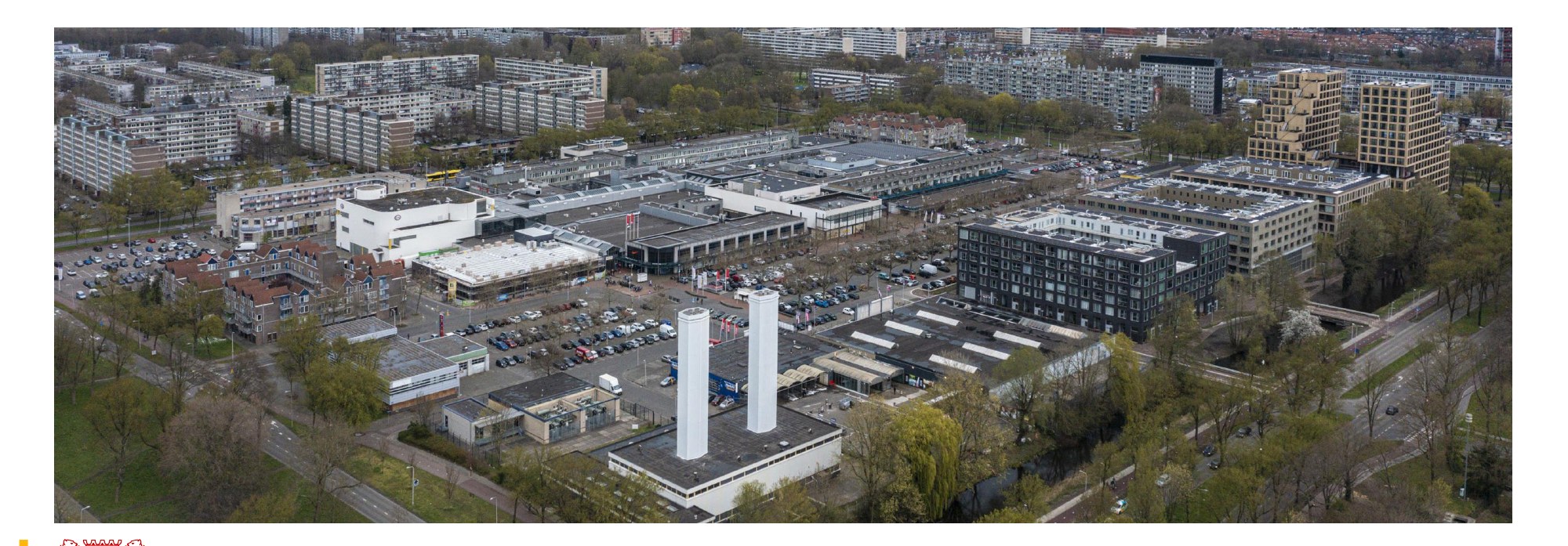 Luchtfoto van het huidige Overvecht Centrum: winkelcentrum, zee van parkeerplaatsen, de kenmerkende witte schoorstenen. Bron: Naslagwerk Masterplanproces Overvecht Centrum, Fase Schetsen (Gemeente Utrecht / Kernteam Overvecht Centrum, januari 2023)